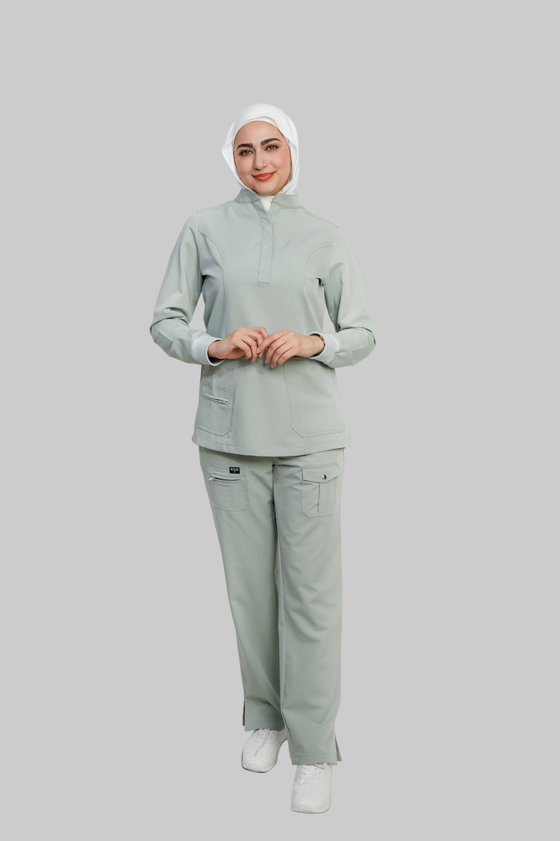 Person wearing a light gray outfit with a hijab on a white background