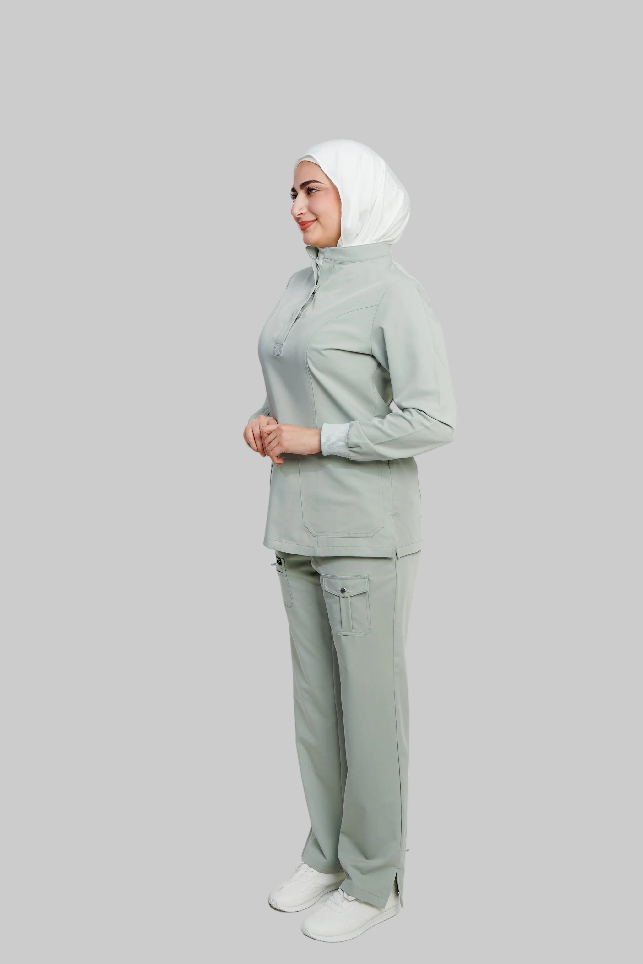 Woman wearing a light gray outfit with a hijab on a white background