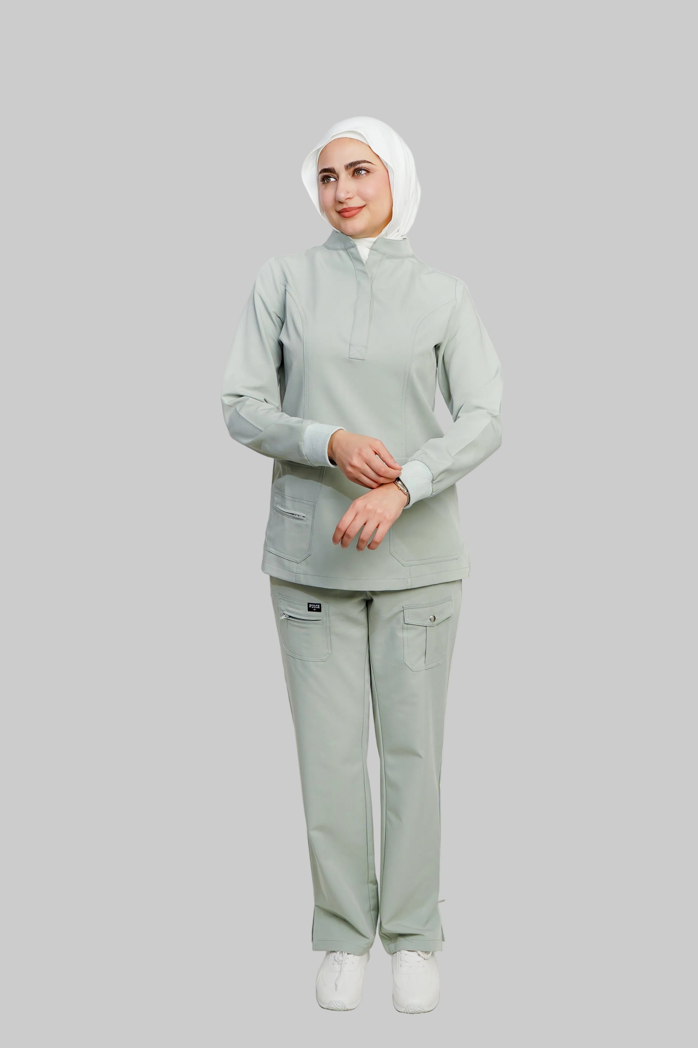 Woman wearing a light green outfit with a hijab on a white background