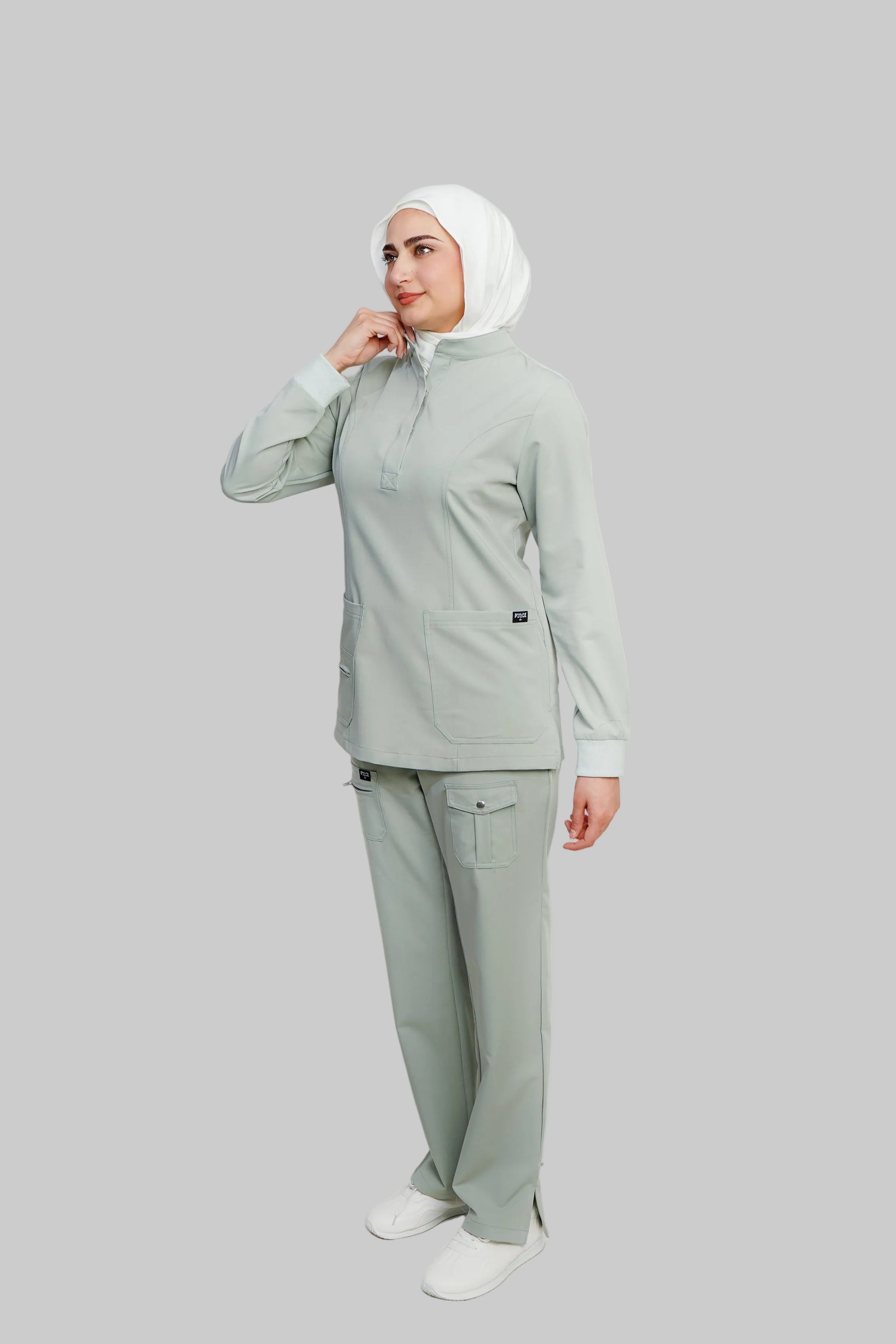 Woman wearing a light green outfit with a hijab on a white background