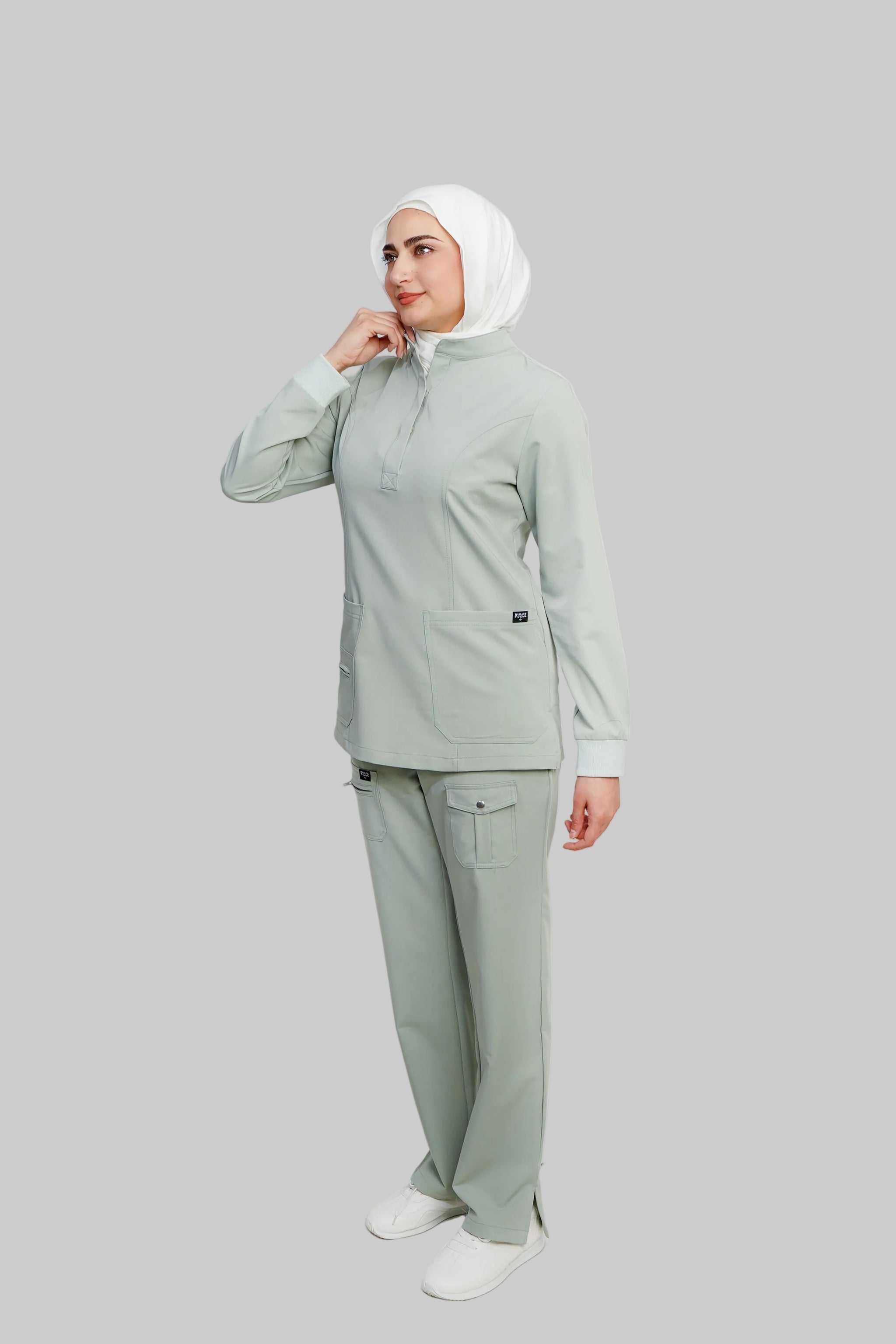 Woman wearing a light green outfit with a hijab on a white background