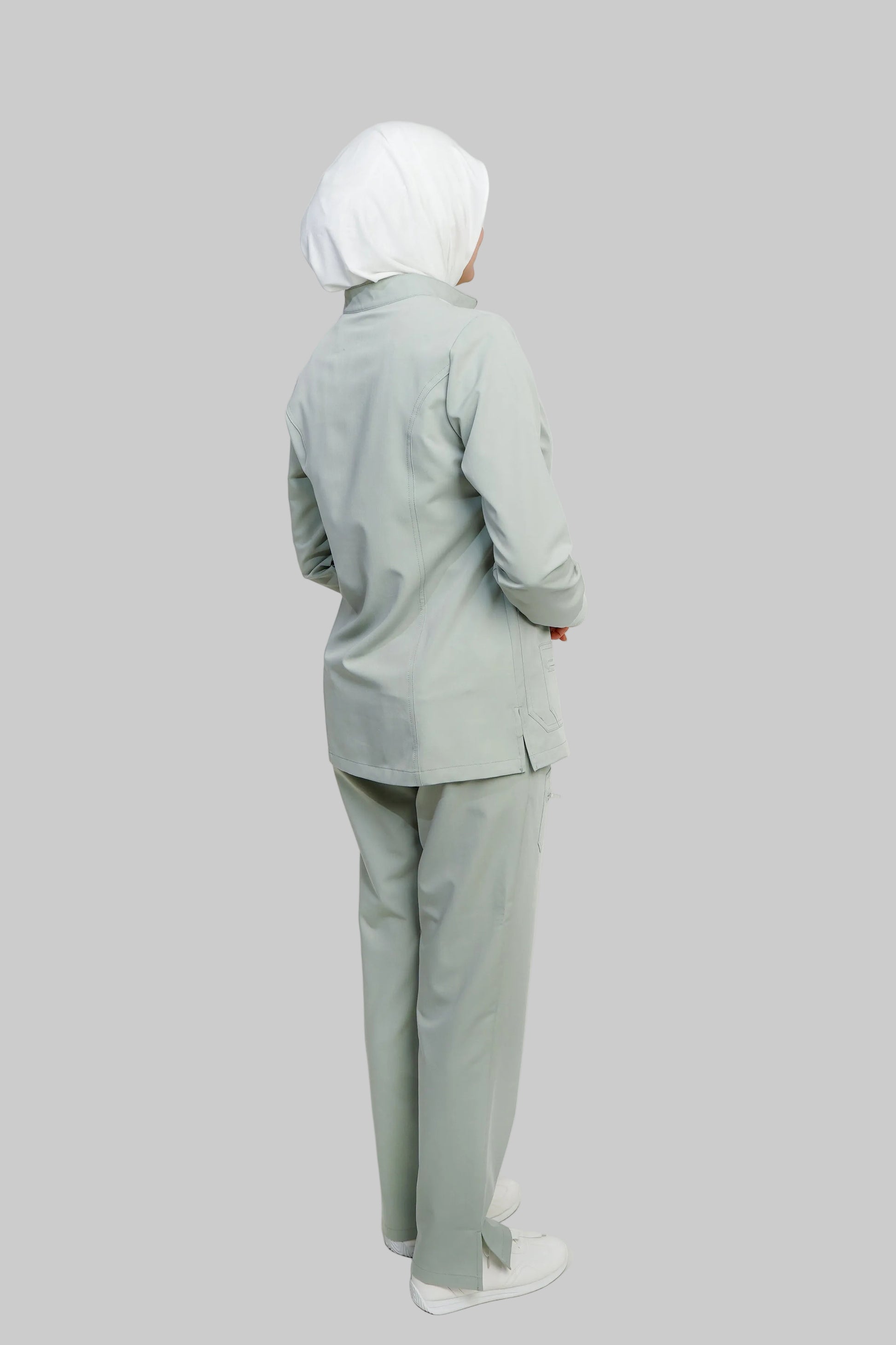 Person wearing a light gray outfit with a hijab on a white background