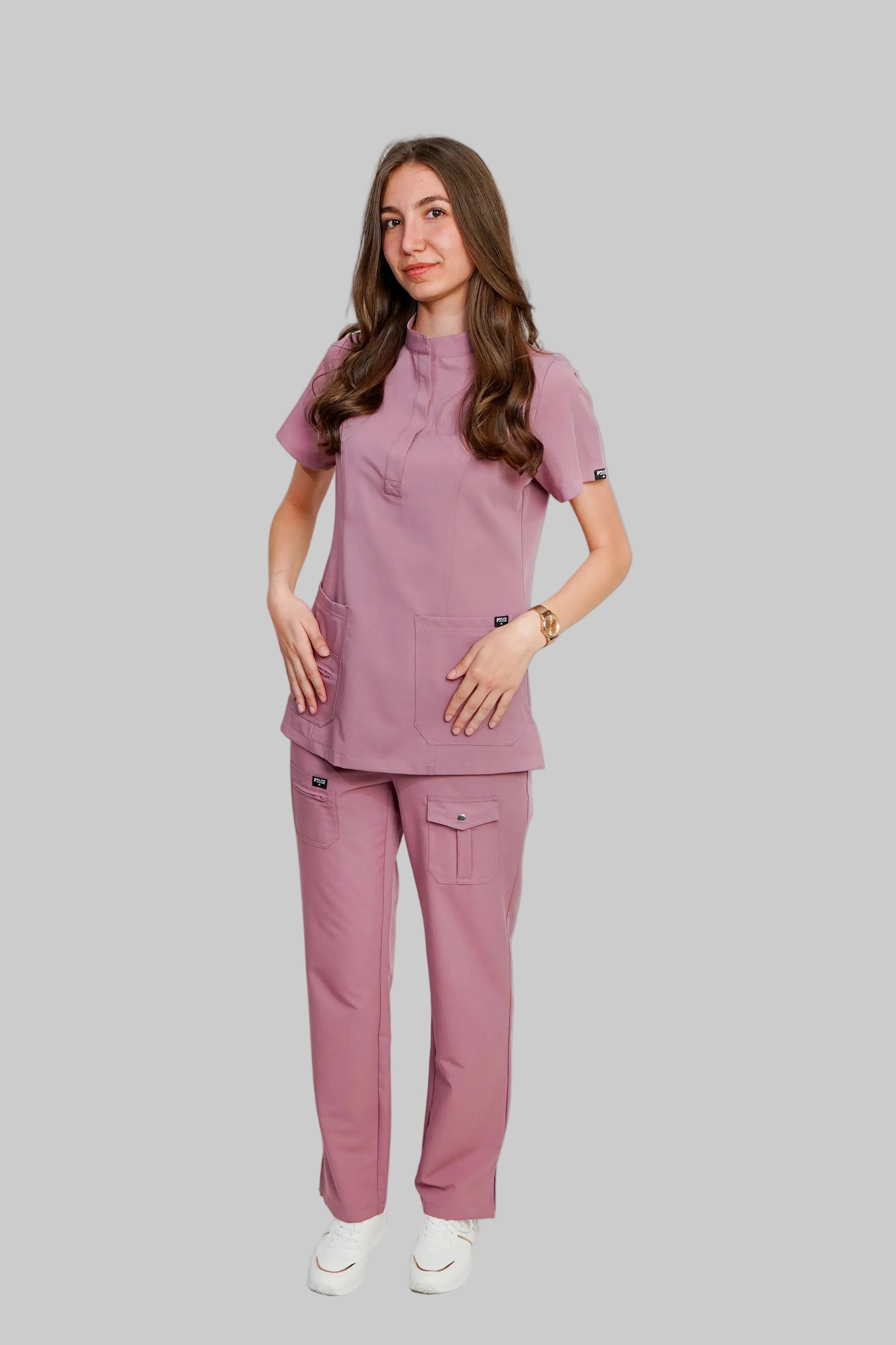 Woman wearing a pink scrub set on a white background