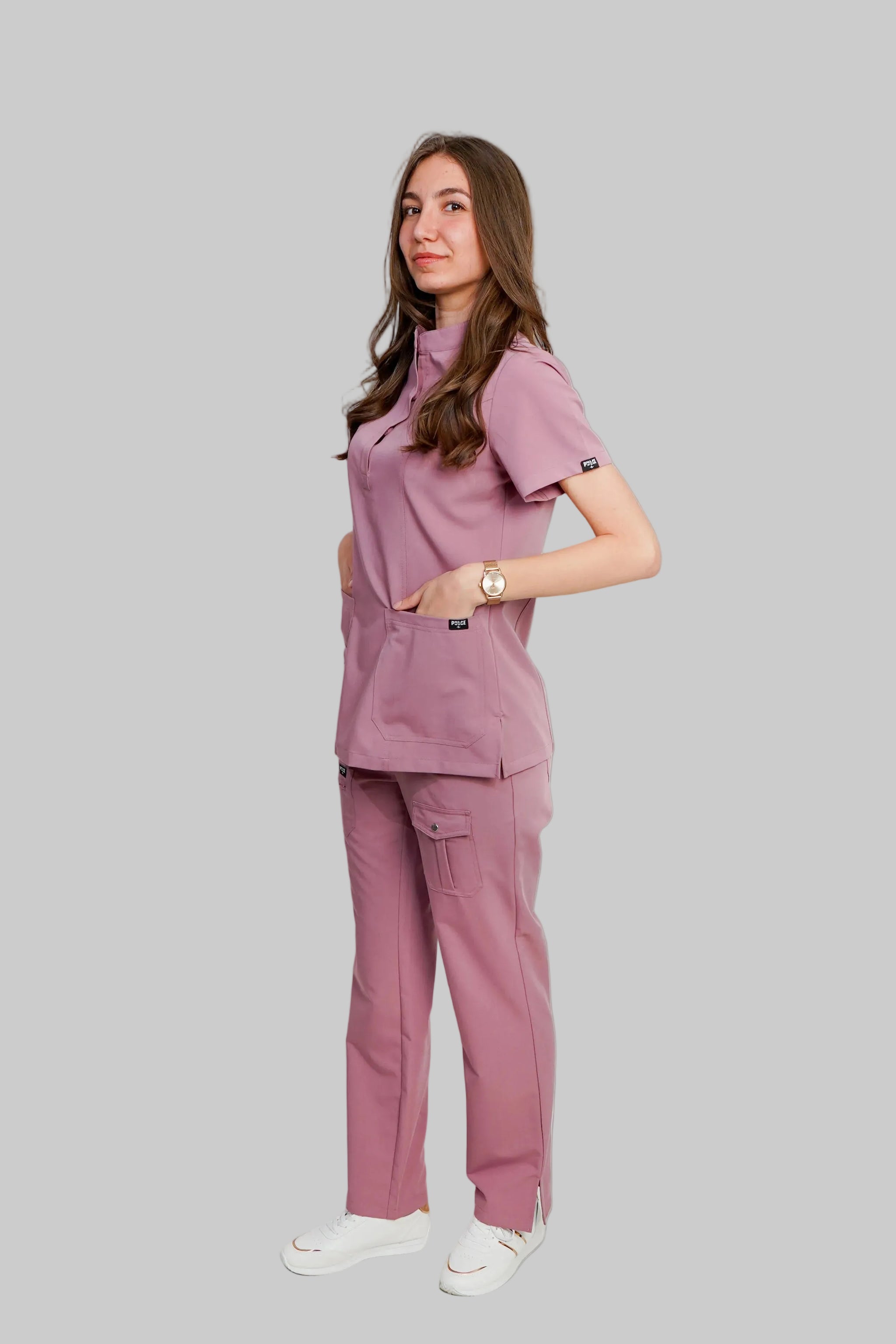 Woman wearing a pink scrub set against a white background