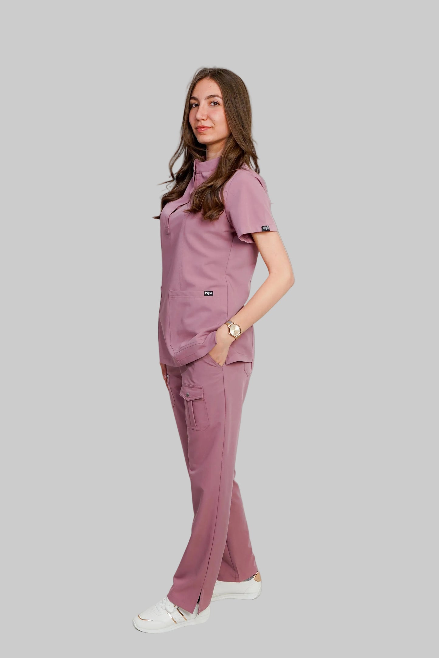 Woman wearing a matching pink scrub set against a white background