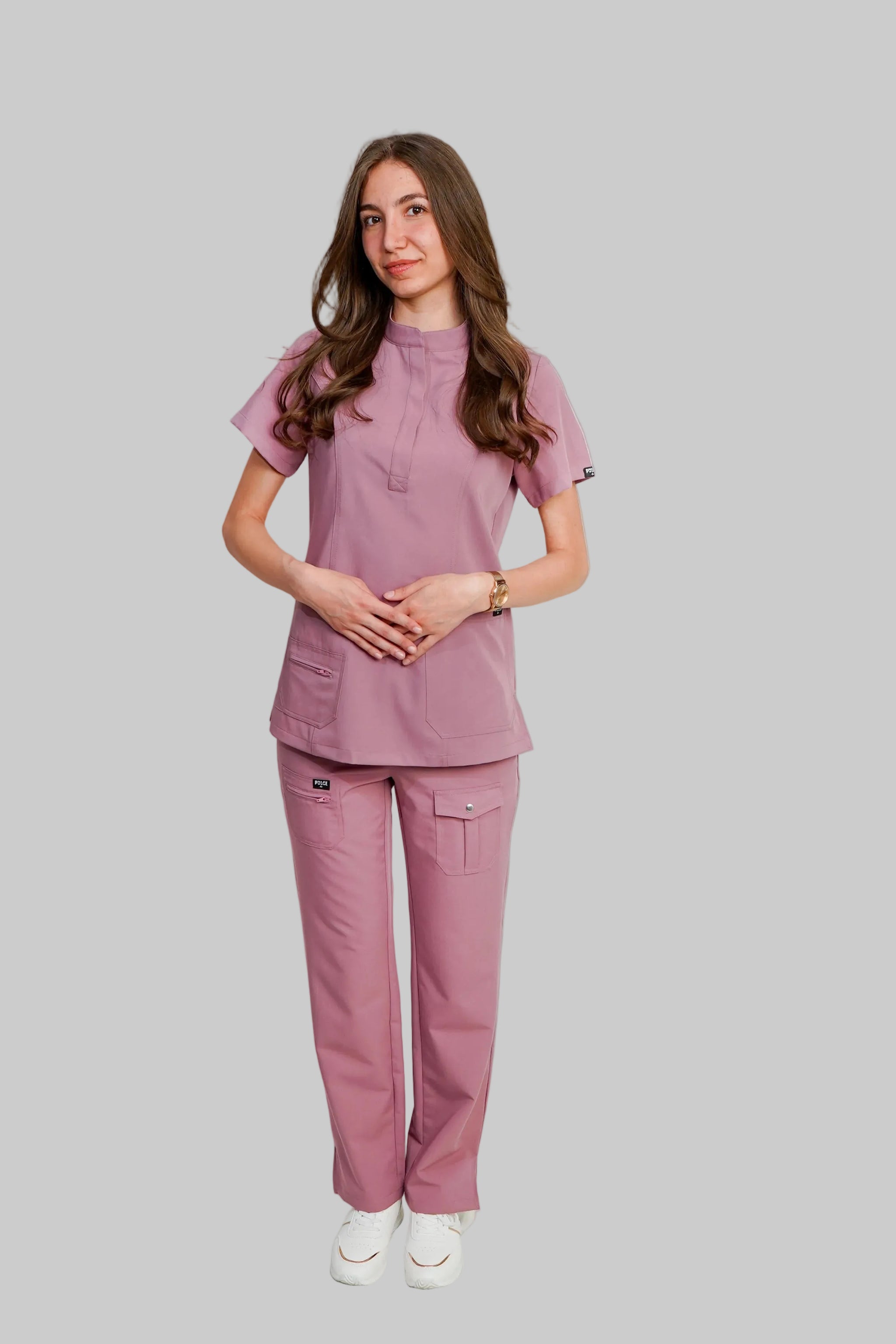 Woman wearing a pink scrub set against a white background