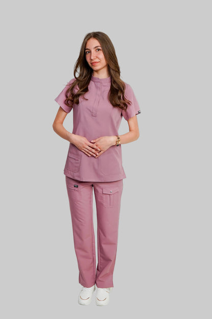 Woman wearing a pink scrub set against a white background