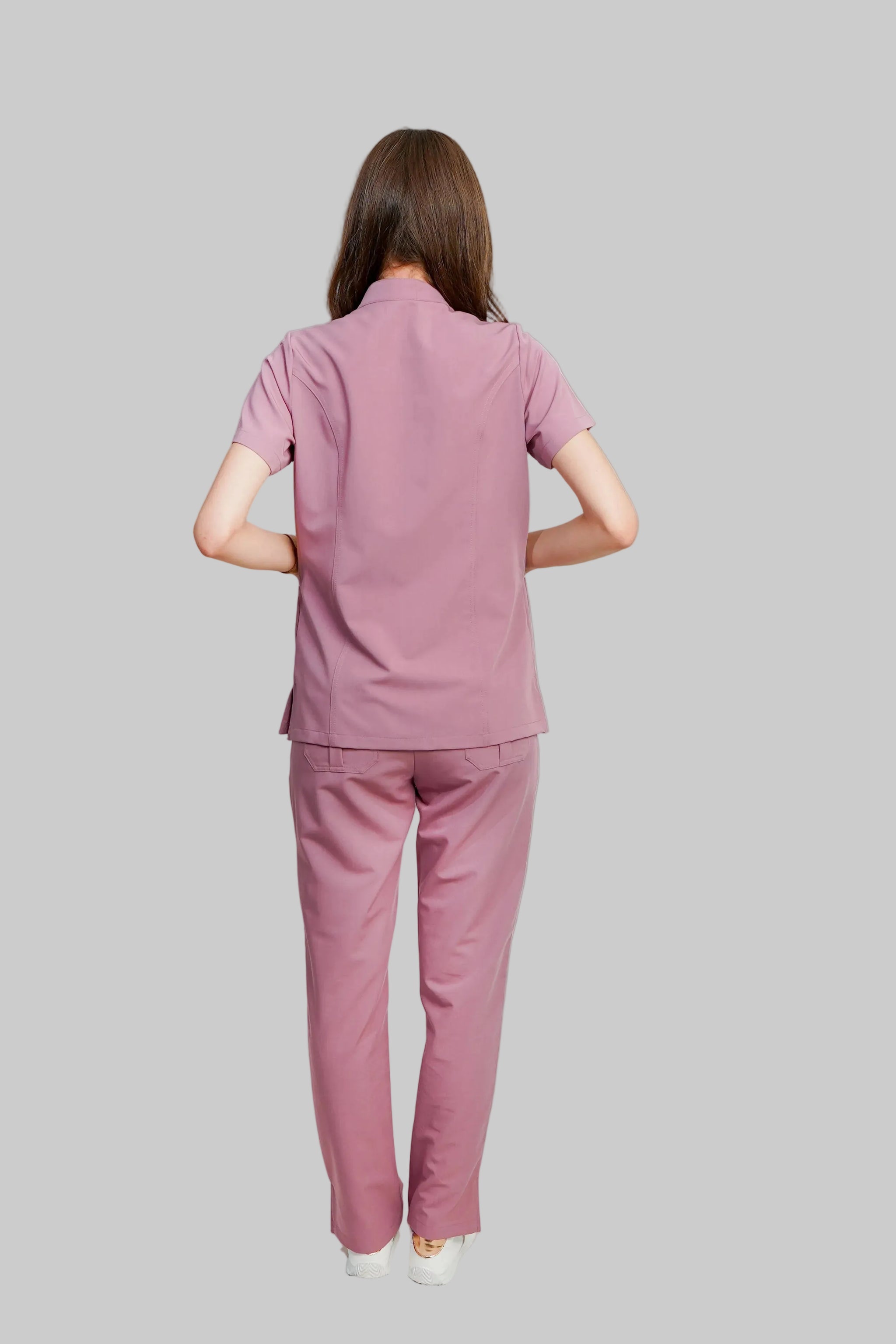 Person wearing a pink scrub set on a white background