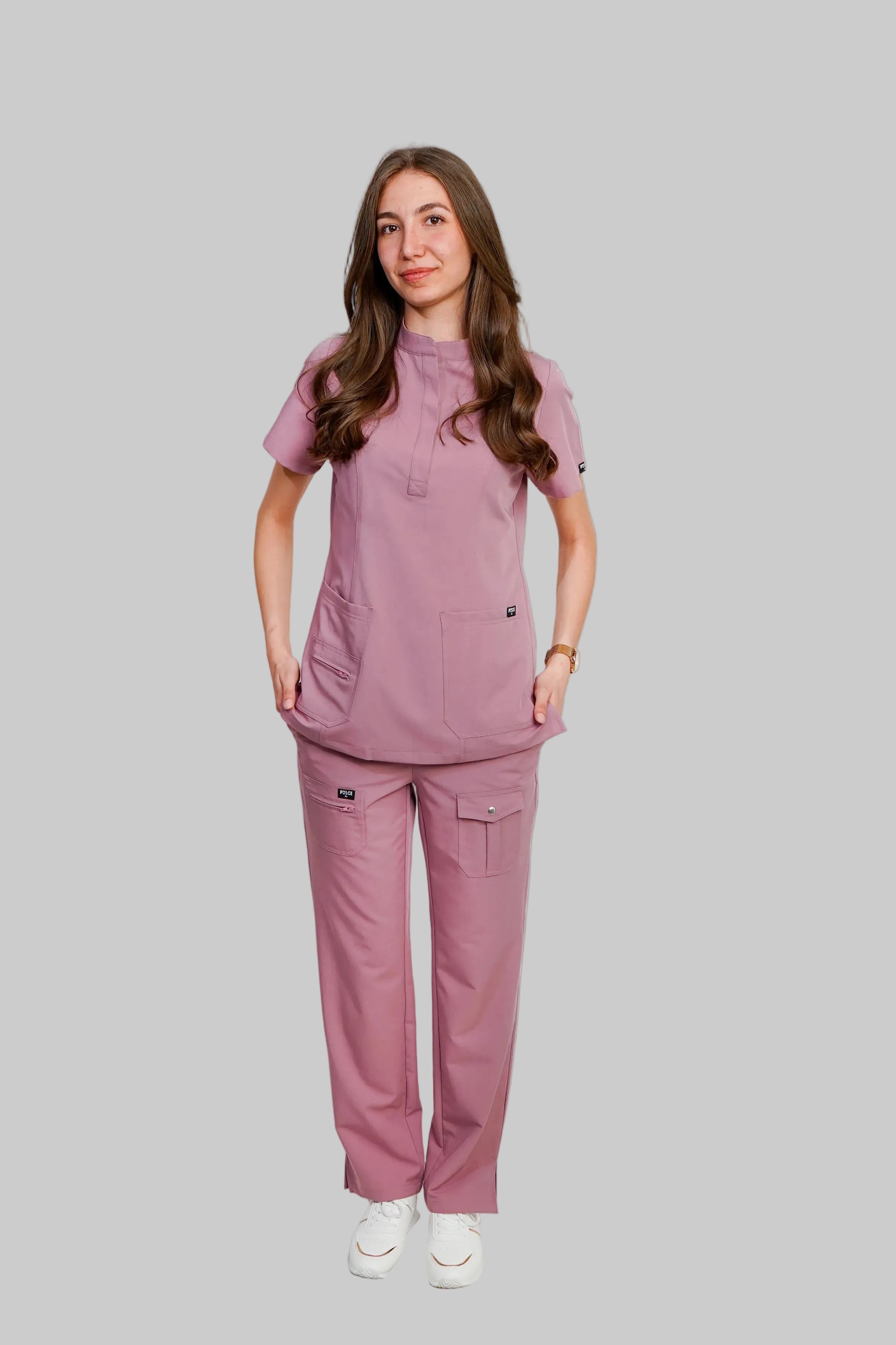 Woman wearing a pink scrub set against a white background