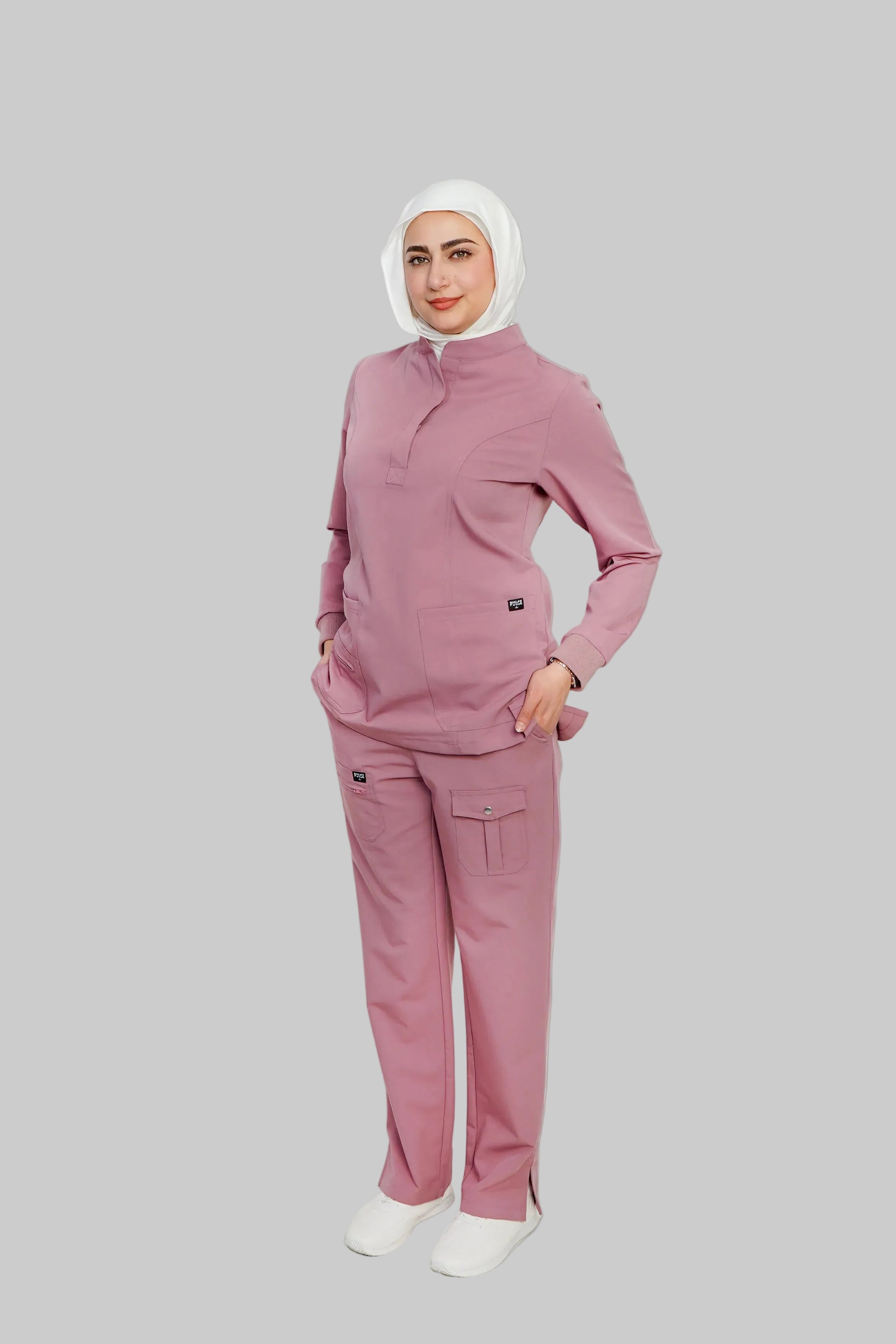 Person wearing a pink outfit with a white hijab on a light gray background