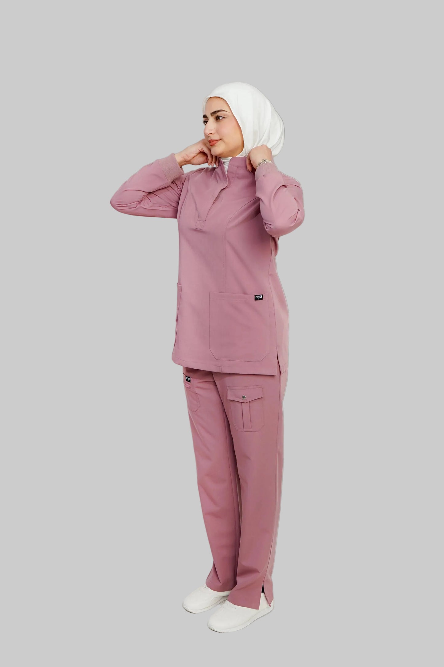 Person wearing a pink outfit with a hijab on a white background