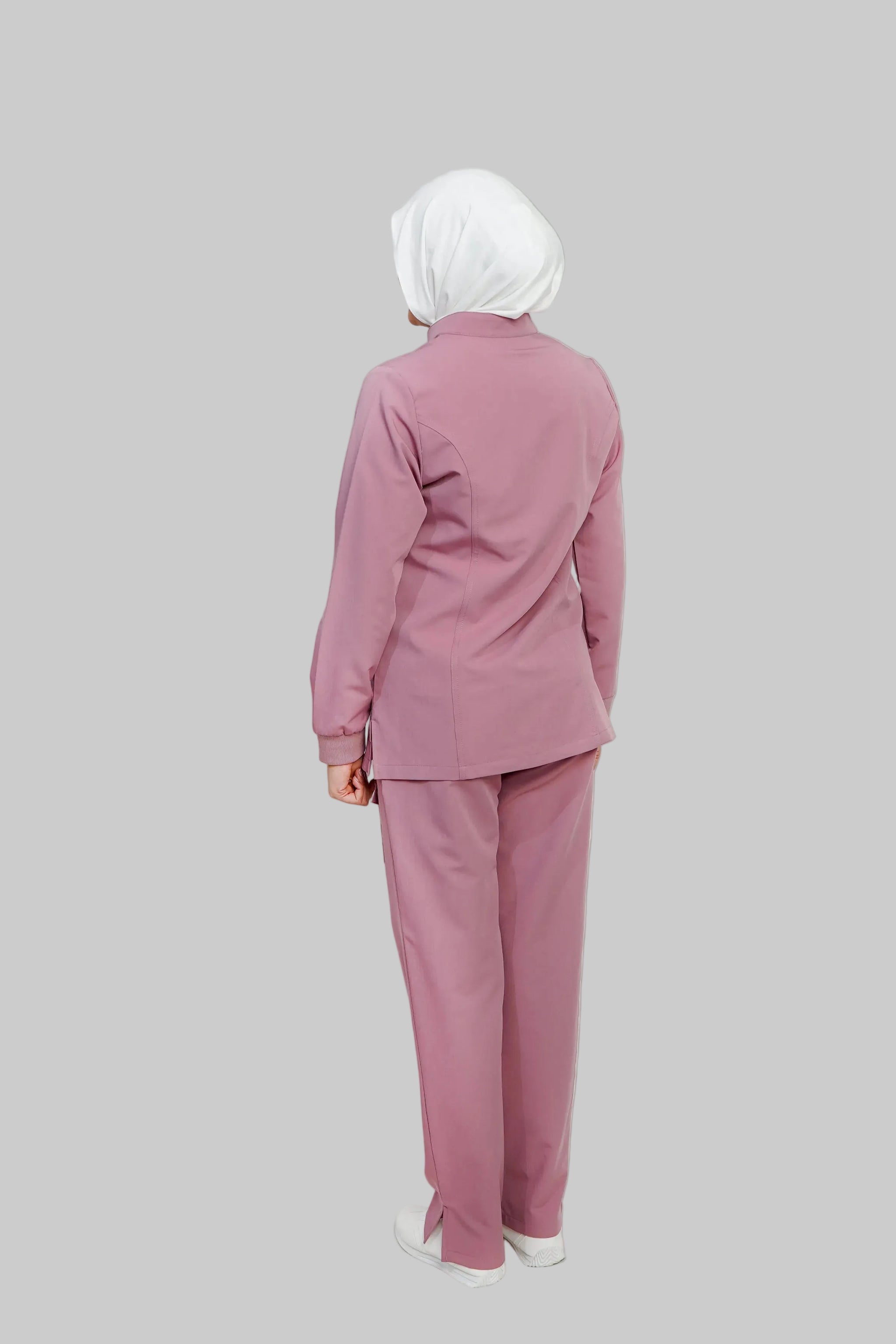 Person wearing a pink outfit with a white hijab on a light gray background