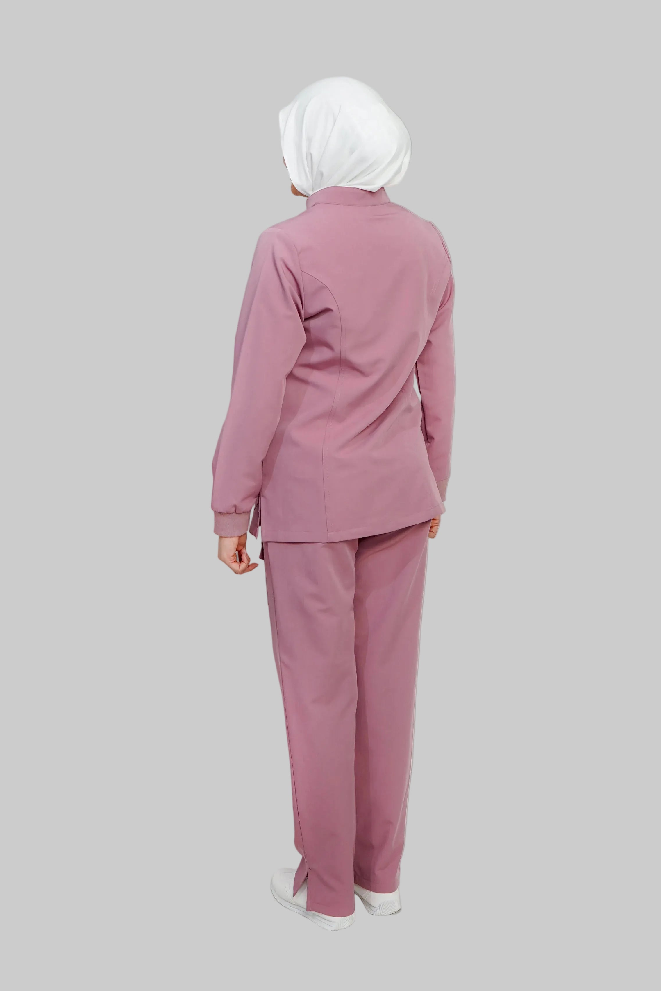 Person wearing a pink suit with a white hijab on a light gray background