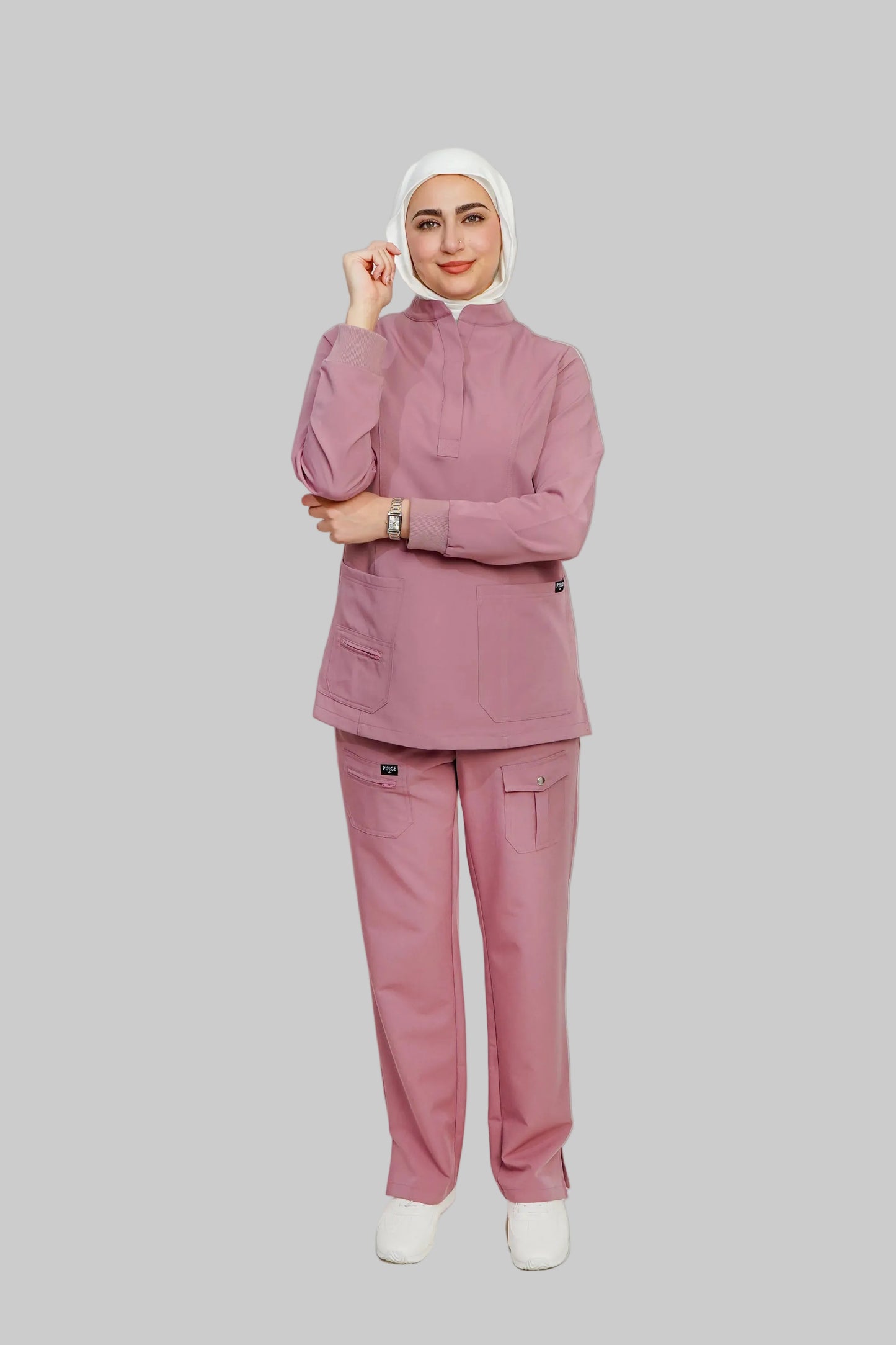 Person wearing a pink scrub set with a hijab on a white background