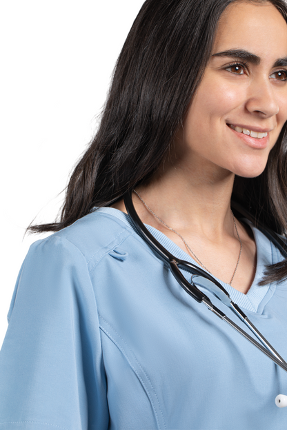 Woman wearing a light blue medical scrub top with a stethoscope around her neck, on a white background.