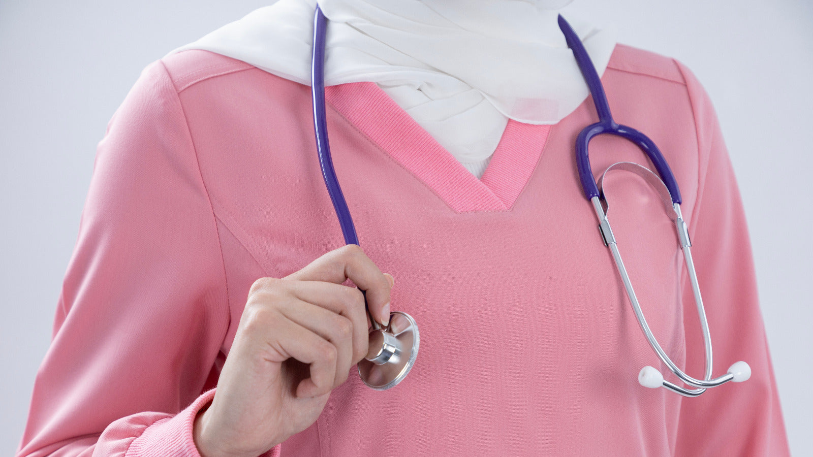 Person wearing a pink outfit with a stethoscope around their neck on a light gray background
